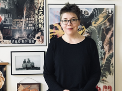 Emily Wros standing in front of framed pictures and posters.