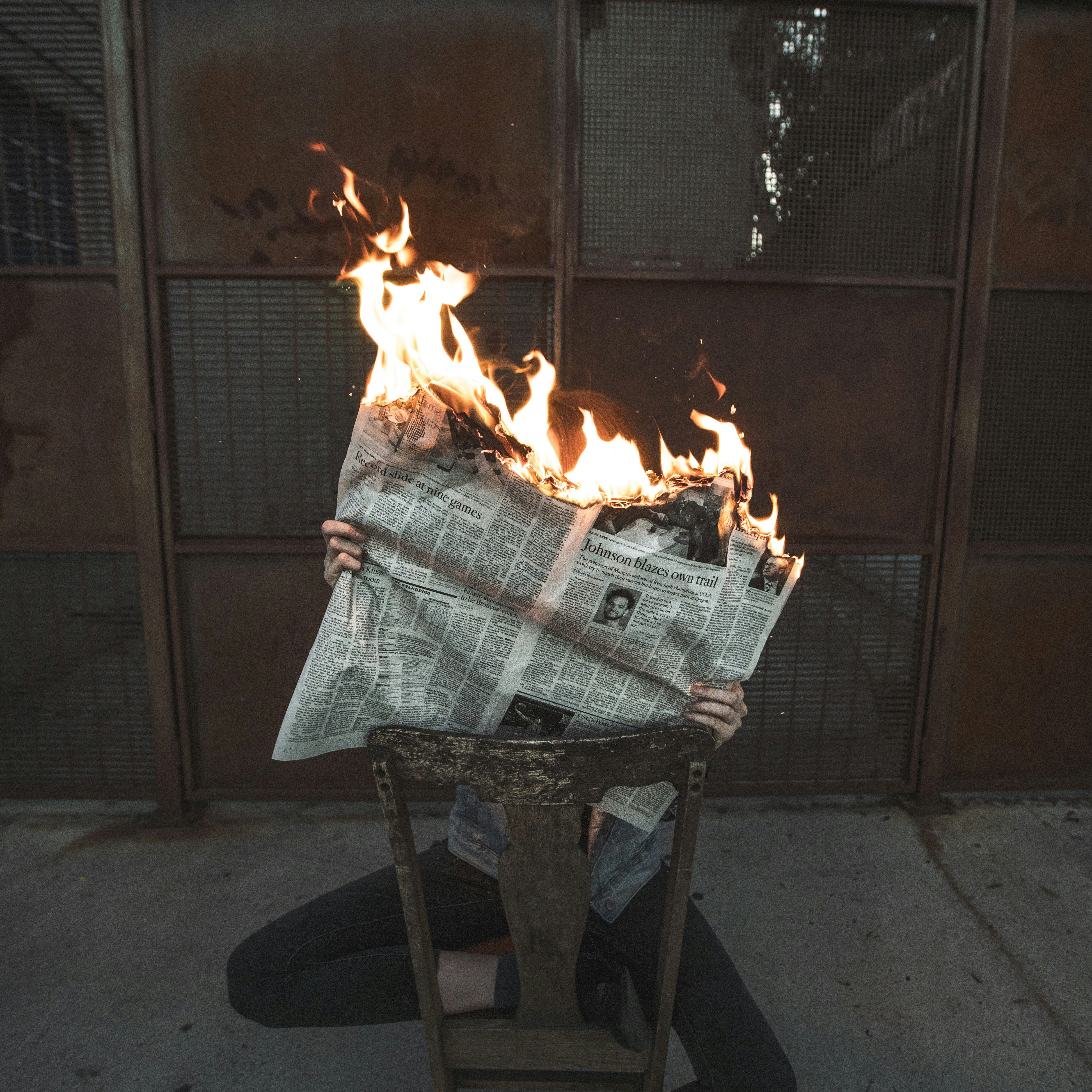 someone with holding a burning newspaper