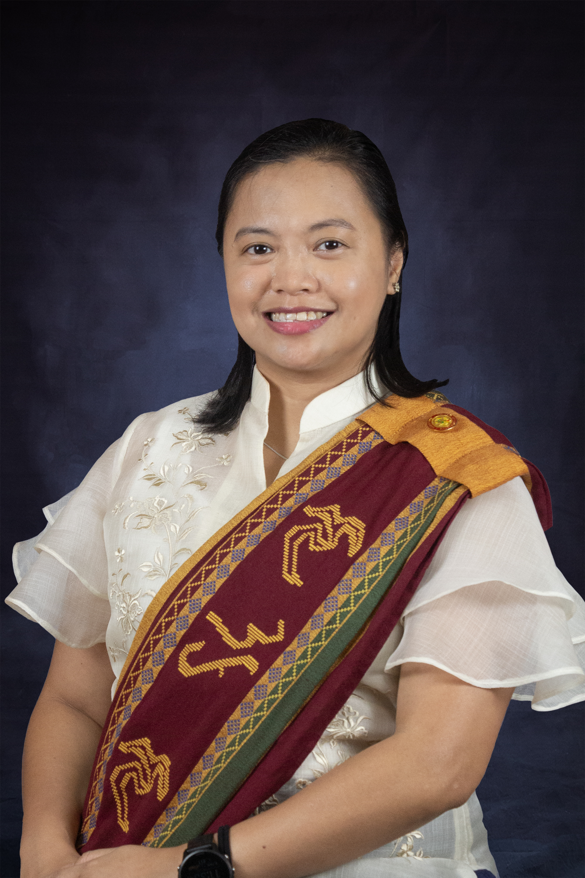 A woman wearing a white shirt adorned with a red and gold sash.