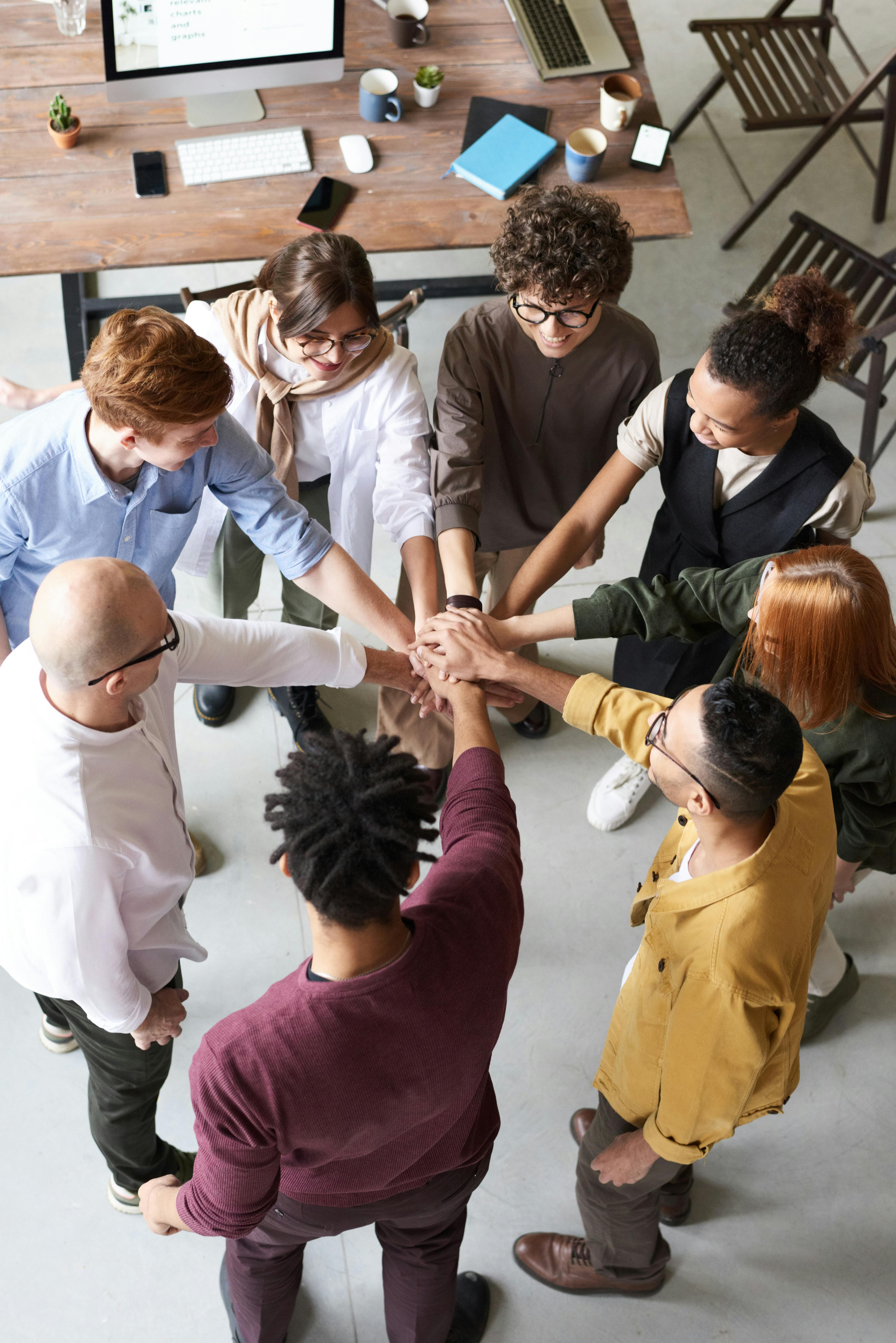 8 people standing in a circle with their hands in the centre