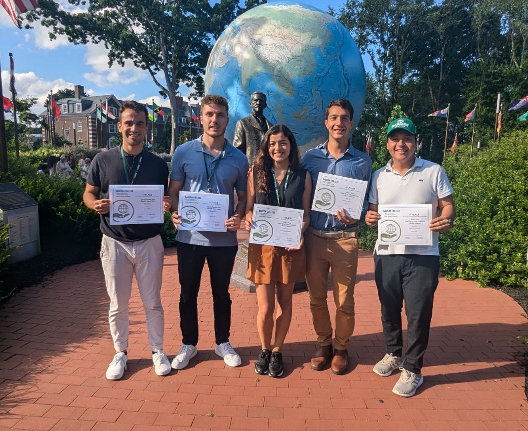 Five people standing next to each other, smiling,, and holding up certificates. A state and a large model globe behind them.