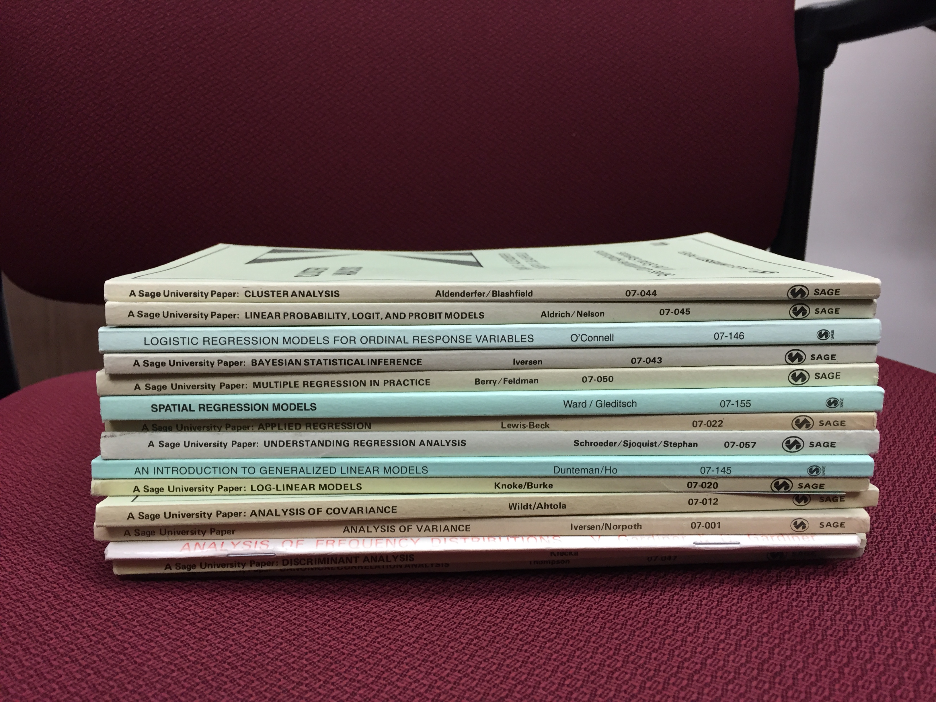 A stack of thin books on a red chair. These are known as Sage's "little green books."